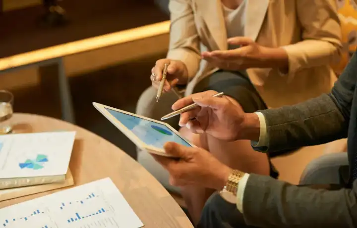 Advisors comparing performance charts on paper and a tablet across a meeting table